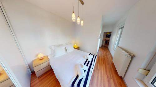Schlafzimmer mit einem weißen Bett und Holzboden in der Unterkunft Le 23 - Strasbourg in Straßburg