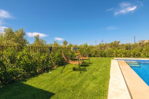 a garden with a table and chairs next to a swimming pool at AKEA VILLAS in Tragaki