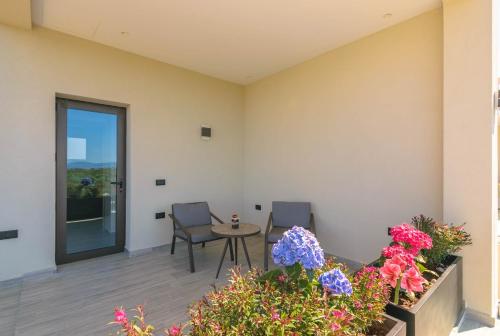 a patio with two chairs and a table and flowers at AKEA VILLAS in Tragaki