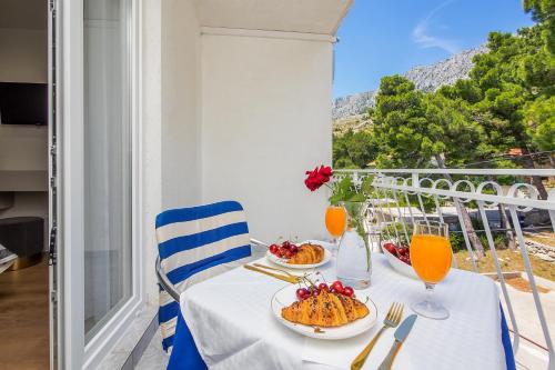 una mesa con 2 platos de comida en el balcón en Skalinada Sea View en Lokva Rogoznica