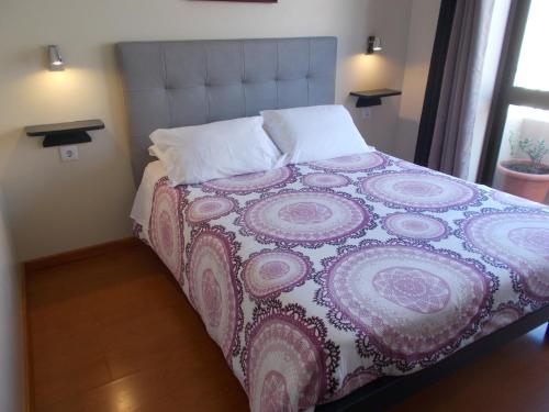 a bedroom with a bed with a purple and white blanket at Abrigo do Portinho in Vila Praia de Âncora