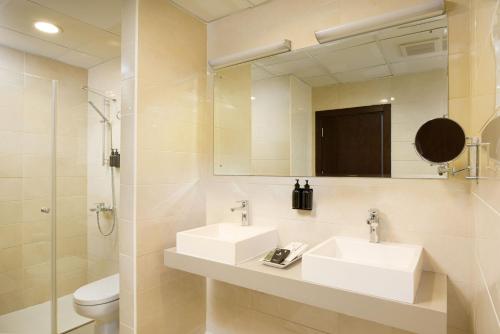 a bathroom with two sinks and a mirror and a toilet at City Hotel Duqm in Duqm
