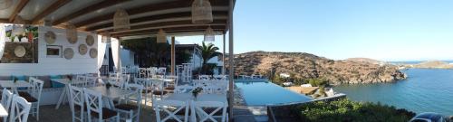 een zwembad met witte tafels en stoelen naast het water bij Paradise Place Sifnos in Chrisopigi