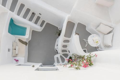 a white house with a staircase and flowers at White Cellar cave houses by Cycladica in Oia