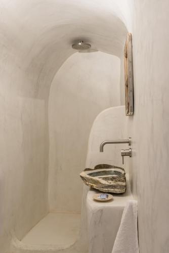 a white bathroom with a sink and a shower at White Cellar cave houses by Cycladica in Oia