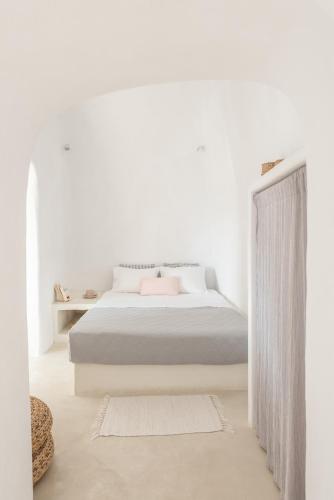 a white bedroom with a bed and a curtain at White Cellar cave houses by Cycladica in Oia