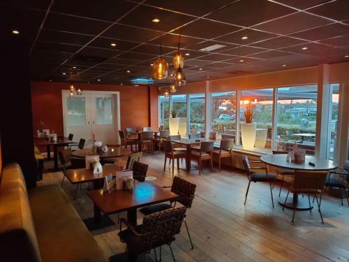 a dining room with tables and chairs and windows at 't VeerHuys in Beusichem