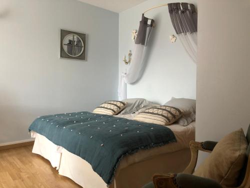 a bedroom with a bed with a blue blanket on it at Le Cèdre Bleu in Grosrouvre