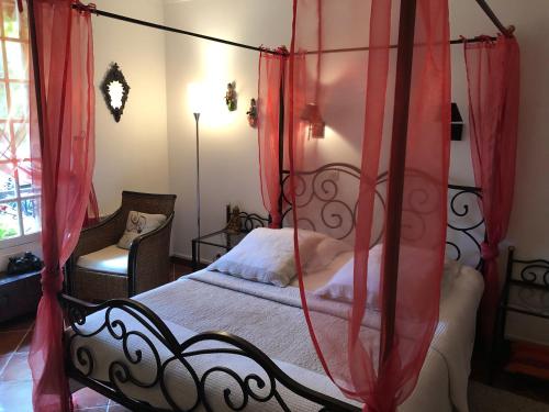 a bedroom with a canopy bed with red curtains at Le Cèdre Bleu in Grosrouvre