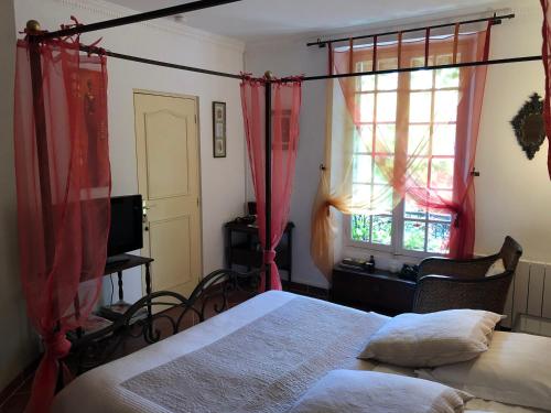 a bedroom with a bed and a window with red curtains at Le Cèdre Bleu in Grosrouvre