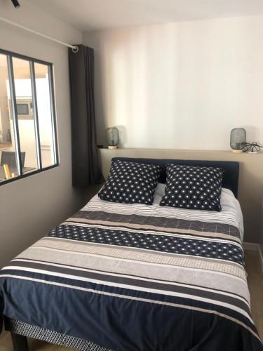 un letto con cuscini bianchi e neri in una camera da letto di Beg-Meil 200 m plage et sentiers T2 avec terrasse a Fouesnant