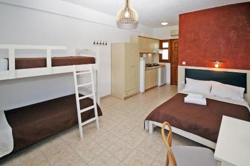 a bedroom with two bunk beds and a kitchen at Studios Stella Vourvourou in Vourvourou