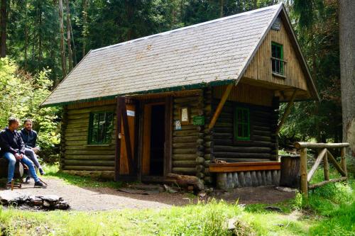 a small log cabin with two people sitting in front of it at Pension zum Ritter in Katzhütte