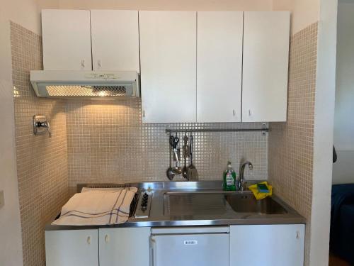 una cucina con armadi bianchi e lavandino di Appartamenti in villa Senia a Favignana