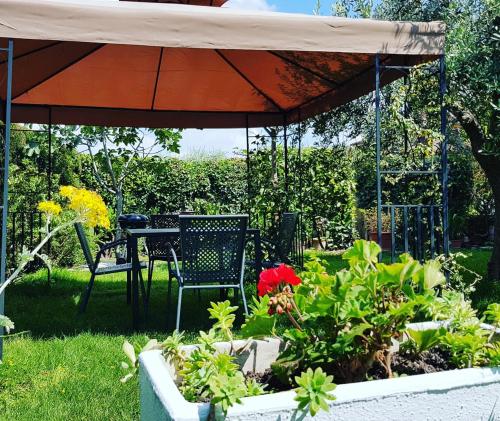 a table and chairs under an umbrella in a garden at Appartamento Dolcitalia in Lazise in Lazise