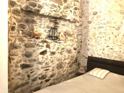 une chambre avec un mur en pierre avec un lit dans l'établissement Appartement de charme au coeur de Saint-Tropez, à Saint-Tropez