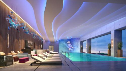 a hotel lobby with a pool and lounge chairs at Hard Rock Hotel Dalian in Dalian