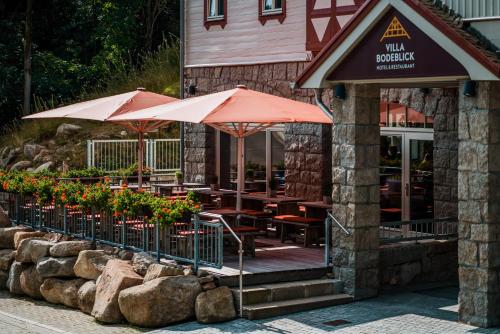 a restaurant with tables and umbrellas in front of a building at Hotel Villa Bodeblick in Schierke
