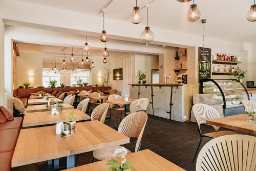 a restaurant with wooden tables and white chairs at Hotel Villa Bodeblick in Schierke