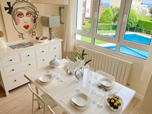 a white dining room table with glasses and a painting at Apartamento Valdenoja Playa Sardinero in Santander