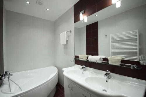 a bathroom with a tub and a sink and a mirror at Prague Central Exclusive Apartments in Prague