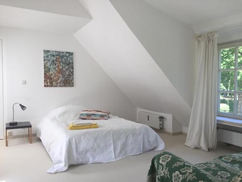 a white bedroom with a bed and a window at Hideaway in Hellwege