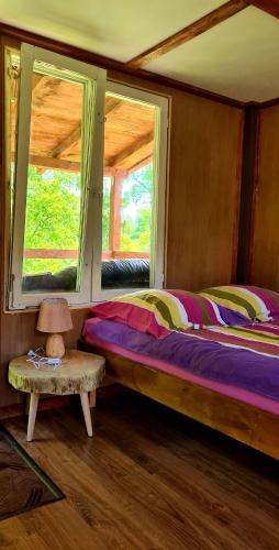 a bedroom with a bed and a table and two windows at Chatka Gargamela in Mikołajki