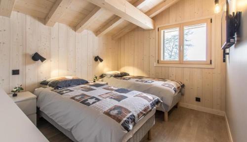 2 Betten in einem Zimmer mit Holzwänden in der Unterkunft Les Ours de Combloux in Combloux