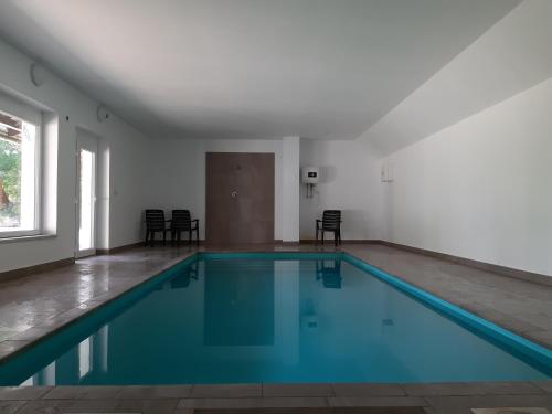 an empty swimming pool in a white room with chairs at Holiday House Vitice 21 in Vitice
