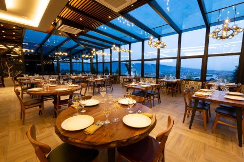 un ristorante con tavoli e sedie in legno e finestre di Avec Hotel a Çanakkale