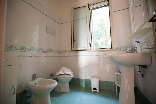 a bathroom with a sink and a toilet and a window at Villa Nadia con splendida vista mare in Castellammare del Golfo