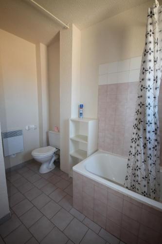 La salle de bains est pourvue d'une baignoire, de toilettes et d'un rideau de douche. dans l'établissement A quelques pas de la plage Belle Maison de vacances, 6 à 8 couchages, 3 chambres, balcon, jardin, parking, 50 m de la mer- PORTIRAGNES PLAGE LXBOSQD, à Portiragnes