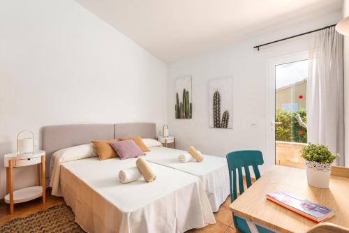 a white bedroom with two beds and a table at Villa Laura in Cala en Forcat
