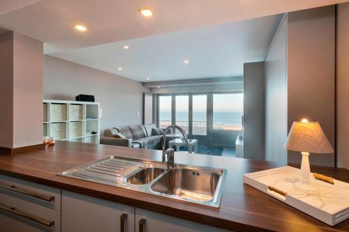 een keuken met een wastafel en een woonkamer bij Montezuma luxe studio met frontaal zeezicht zonder aparte slaapkamer in Oostende
