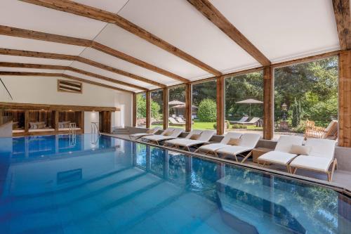 an indoor swimming pool with white chairs and windows at ADLER HÄUSERN Gourmet & Spa Hotel in Häusern