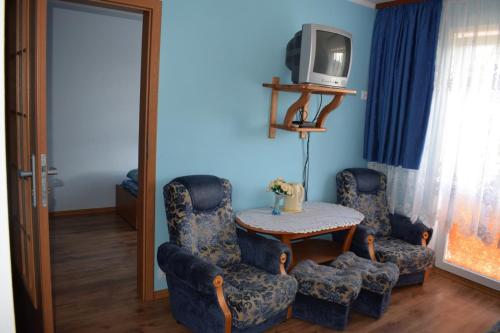 Cette chambre dispose de 2 chaises, d'une table et d'une télévision. dans l'établissement U Rybaka (pokoje), à Jezierzany