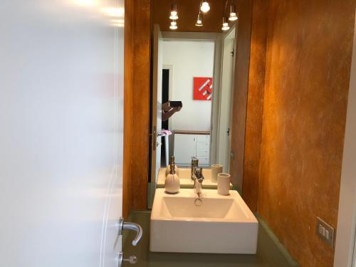 La salle de bains est pourvue d'un lavabo blanc et d'un miroir. dans l'établissement Appartamento con Piscina a Lazise, à Lazise