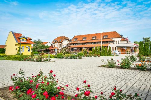 un grupo de casas y flores en un patio en Hotel Rózsa Csárda Bungalow & Caravan Park en Hegyeshalom