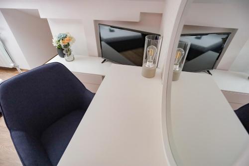a room with a blue chair and two windows at Different Apartments in Niš
