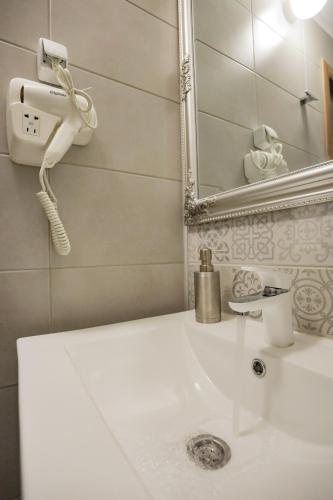 a bathroom sink with a phone and a mirror at Different Apartments in Niš