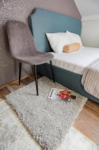 a bedroom with a bed with a chair and a rug at Different Apartments in Niš