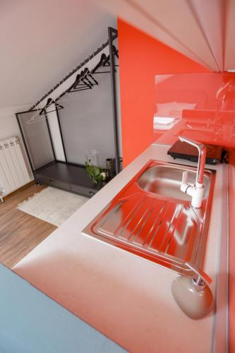 a kitchen with a sink and a red wall at Different Apartments in Niš