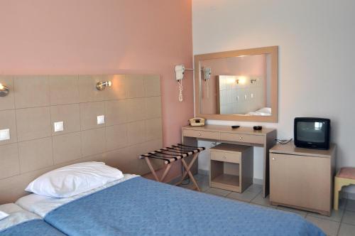 a bedroom with a bed and a sink and a mirror at Hotel Aris in Tolo