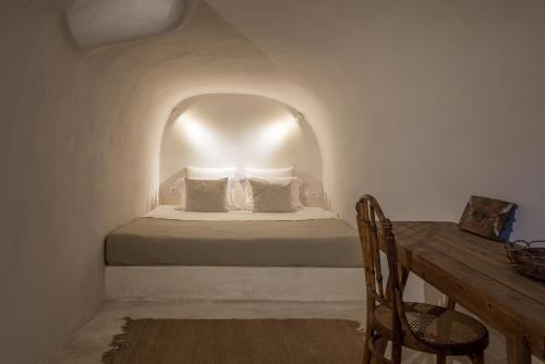 a bedroom with a bed and a wooden table at The sculptor's house by Cycladica in Oia
