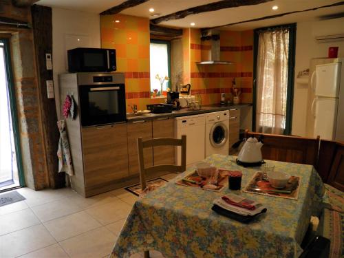 a kitchen with a table and a kitchen with a refrigerator at Les Inseparables in Sévérac-lʼÉglise