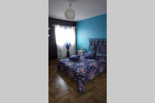 Maison adossée في LʼAiguillon-sur-Vie: غرفة نوم بسرير مع جدار ازرق