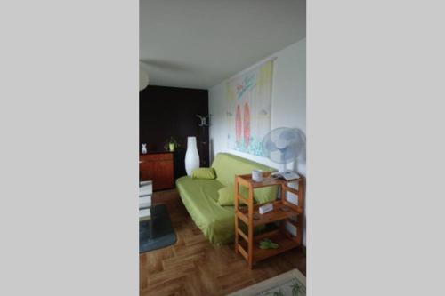 ein Wohnzimmer mit einem grünen Sofa und einem Tisch in der Unterkunft Maison adossée in LʼAiguillon-sur-Vie