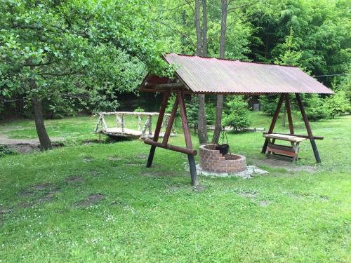 a gazebo with a roof and a bench in a park at Cabana Khaliope in Floroaia Mică