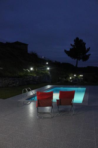 two chairs sitting next to a swimming pool at night at CASA das Leiras in Vieira do Minho