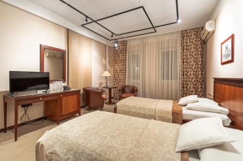 ein Hotelzimmer mit 2 Betten und einem TV in der Unterkunft The Regent Club Hotel in Niš